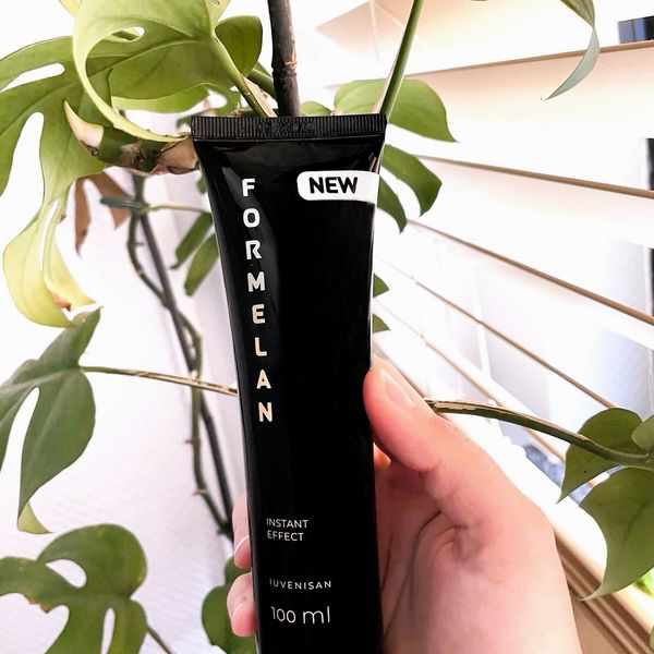 Fekete Formelan gél 100 ml-es tubusa kézben, zöld növény előtt
